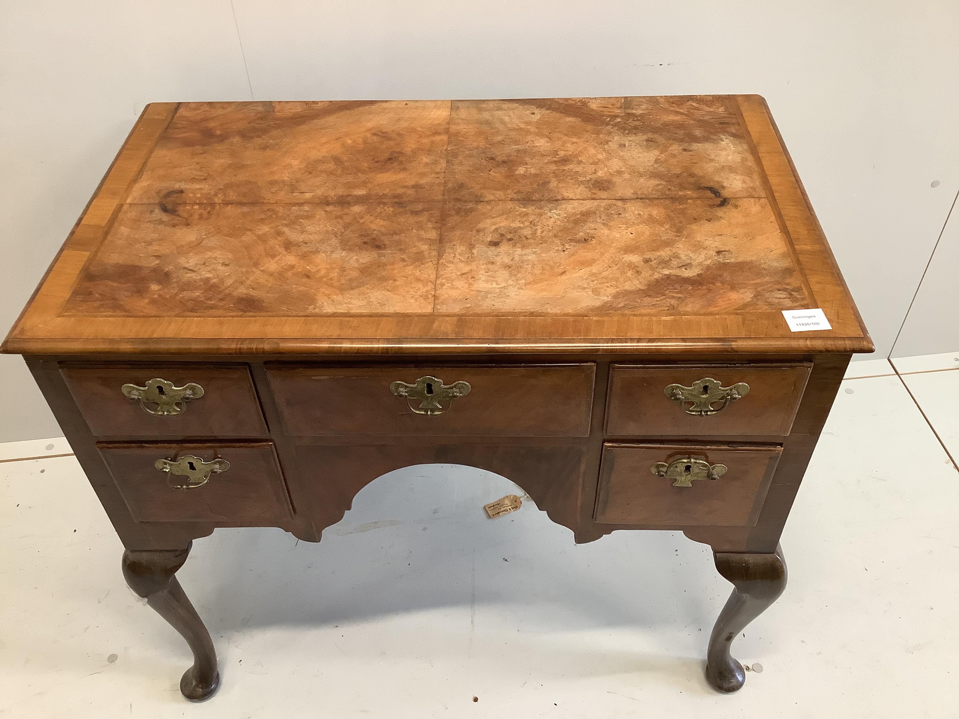 A Queen Anne revival feather banded walnut kneehole dressing table (front leg a/f), width 88cm, depth 50cm, height 75cm